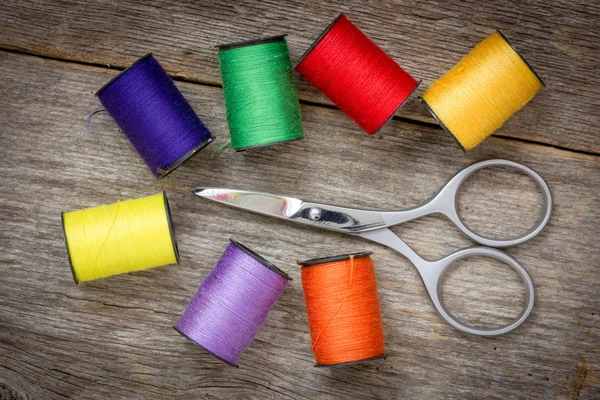 Scissors and spools of colored thread — Stock Photo, Image