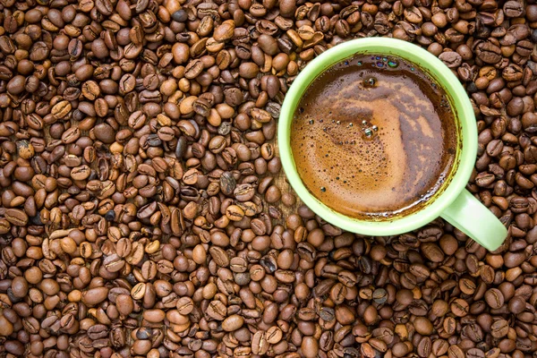 Koffiebonen en groene cup — Stockfoto
