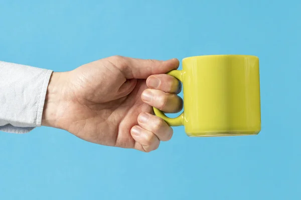 Hand Van Een Man Met Een Groene Mok Blauwe Achtergrond — Stockfoto