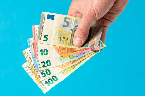 手は青い背景にユーロ紙幣を保持します ユーロマネー — ストック写真