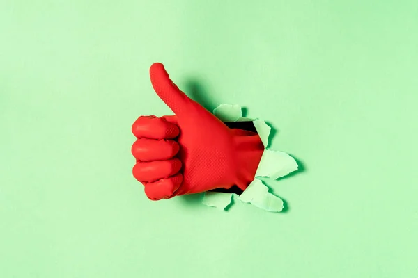 Hand Red Rubber Glove Thumb Gesture Hole Blue Paper Wall — Stock Photo, Image