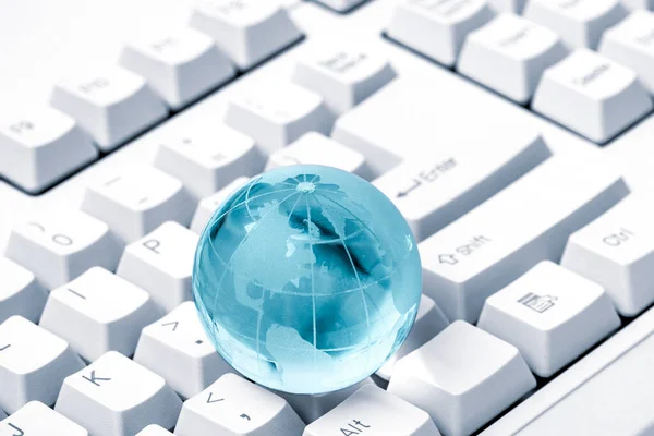 Blue crystal globe of the Earth on a computer keyboard. Global & international business concept. World connected. Social network concept.
