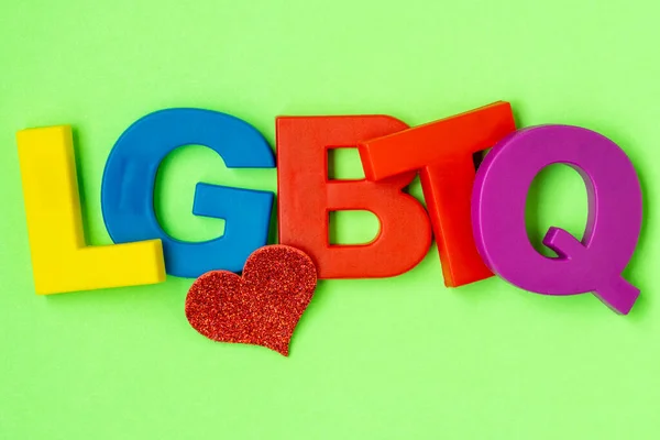 カラフルなプラスチックの文字と緑の背景に少し赤いハートから作られた言葉Lgbtq コンセプト Lgbtコミュニティ — ストック写真