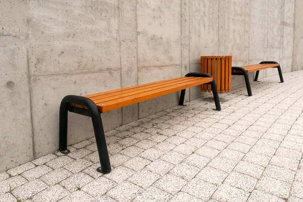 Two Wooden Benches Garbage Bin Background Concrete Wall — Stockfoto