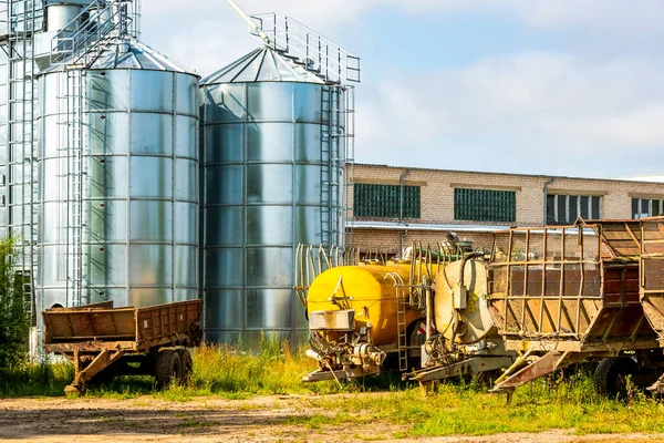 Farm yard with agricultural trailers, tanks and building for storage and drying of grain crops