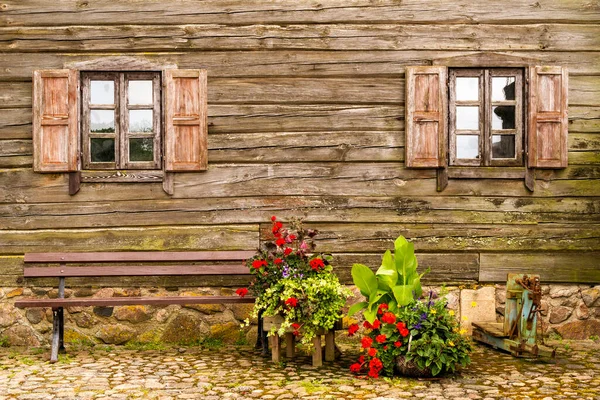 Old wooden house facade with windows,bench and flowers