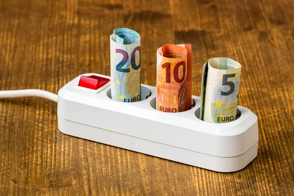 Rising energy costs concept. Euro money banknotes plugged into a white power strip. High energy costs in Europe. Electricity bill payment.