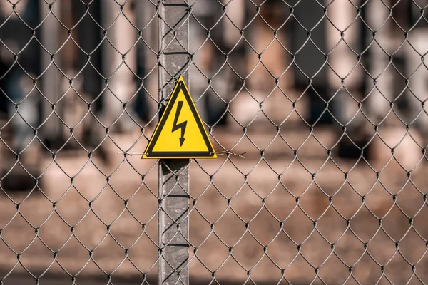 Electrical hazard sign placed on a fence of an electrical substation. High voltage electrical outdoor substation.