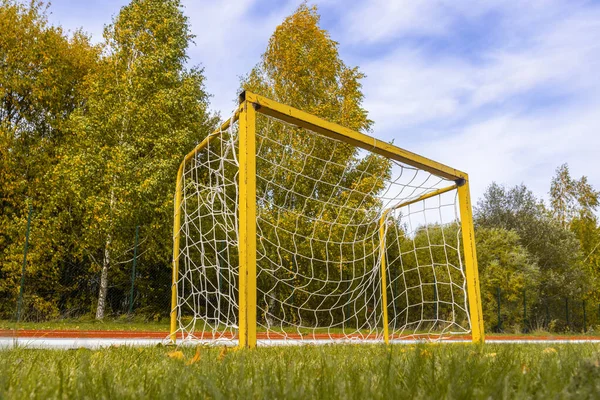 Small yellow football goals in a stadium during autumn season. Football goals for kids training.