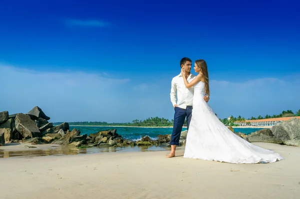 Feliz recém-casados em uma praia selvagem — Fotografia de Stock