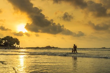 Baba ve iki çocuk gün batımında denize