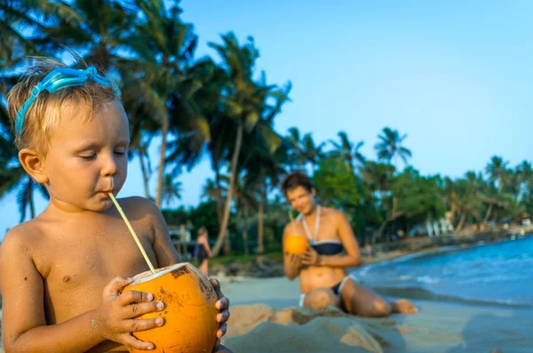 Piccolo sulla spiaggia e bere latte di cocco — Foto Stock