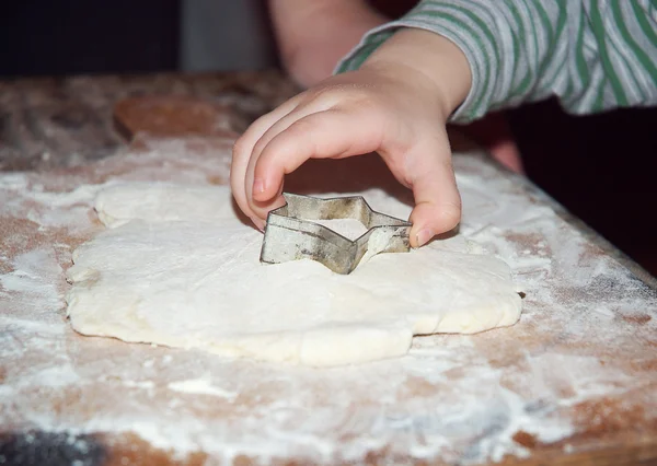 Baby greift nach geformtem Keksteig. lizenzfreie Stockbilder