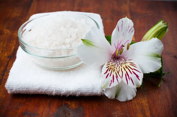 Toalha branca, sal aromático e flor — Fotografia de Stock