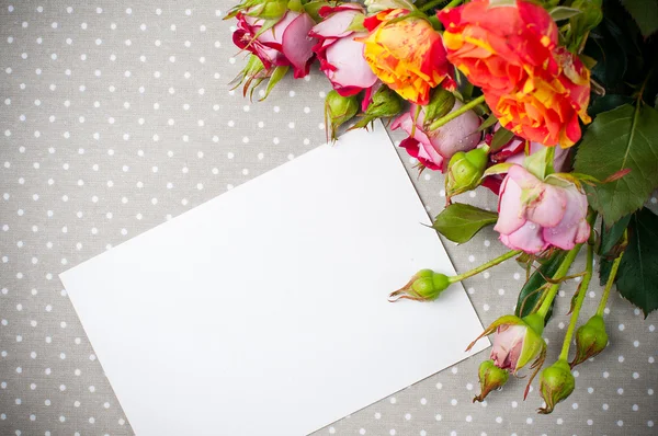 Rosen und weißer Karton auf grauem Stoff — Stockfoto