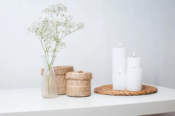 Flores, velas brancas e duas cestas fechadas Imagem De Stock