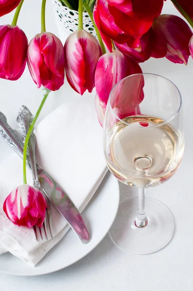 Glass of white wine and a festive table setting — Stock Photo, Image