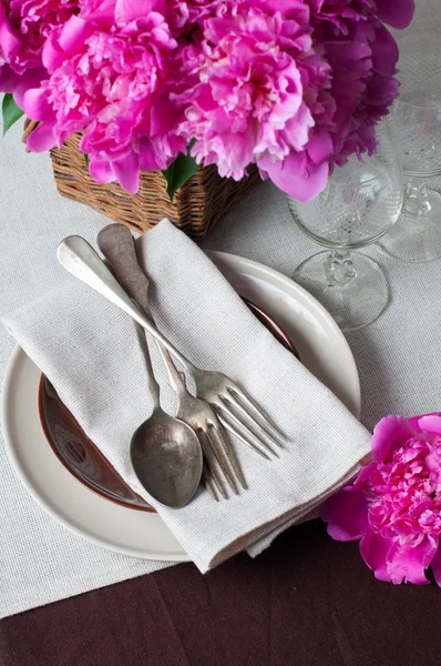 Configuração de mesa com peônias rosa, talheres vintage e mesa marrom — Fotografia de Stock