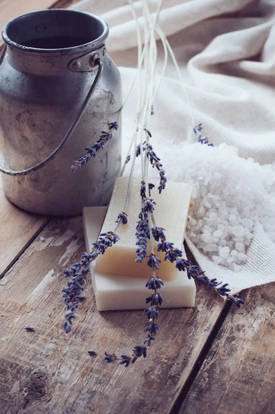 Soap, lavender, salt and old can on wooden board — Stock Photo, Image