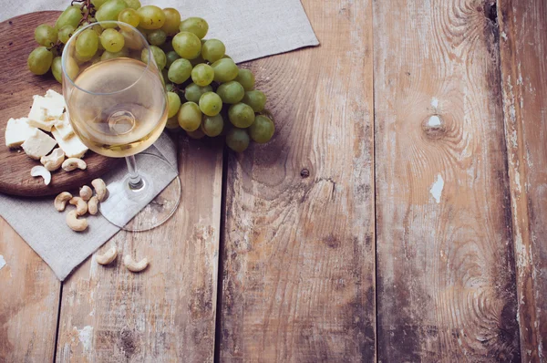 Bicchiere di vino bianco, uva, anacardi e formaggio morbido — Foto Stock