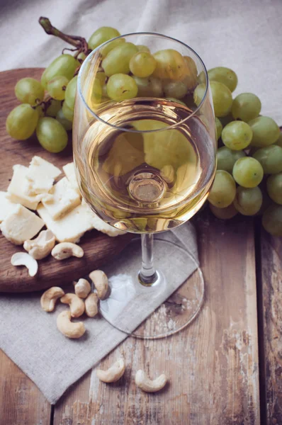 Bicchiere di vino bianco, uva, anacardi e formaggio morbido — Foto Stock