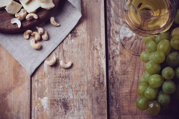 Bicchiere di vino bianco, uva, anacardi e formaggio morbido — Foto Stock