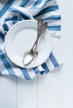 çatal bıçak takımları, porselen tabak ve beyaz keten peçete