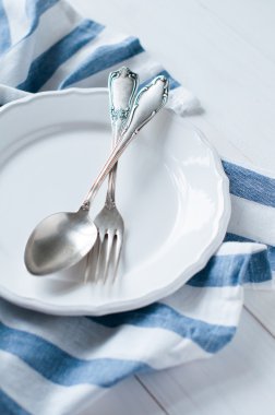 çatal bıçak takımları, porselen tabak ve beyaz keten peçete