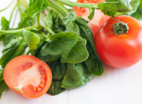 Tomatoes and spinach leaves — Stock Photo, Image