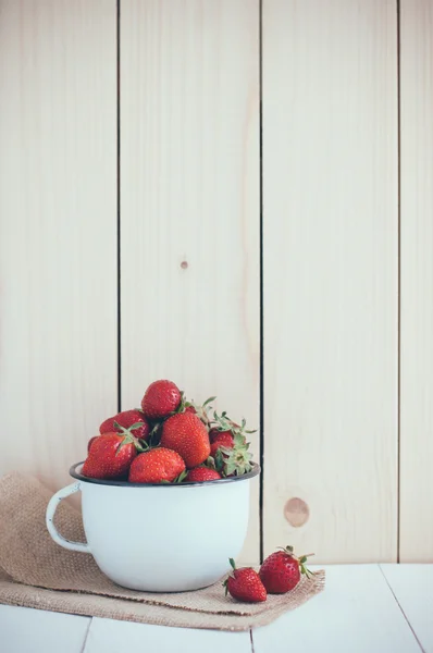 strawberries in white enamel mug