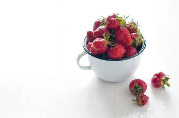 Aardbeien in wit geëmailleerd mok — Stockfoto