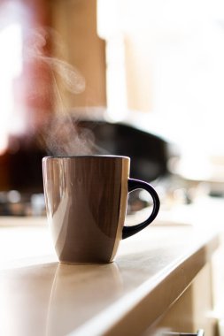 Kahverengi kahve fincanı mutfak masasının üzerinde gerçek gün ışığı ve buharla
