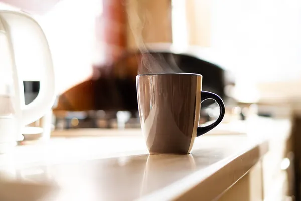 Braune Kaffeetasse auf Küchentisch mit echtem Tageslicht und Dampf — Stockfoto