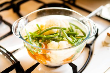 Sebze çorbalı şeffaf cam tava, fırında taze sıcak yemek.