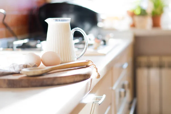 Leche fresca y huevos en tablero de madera en el interior de la cocina casera real con luz natural —  Fotos de Stock