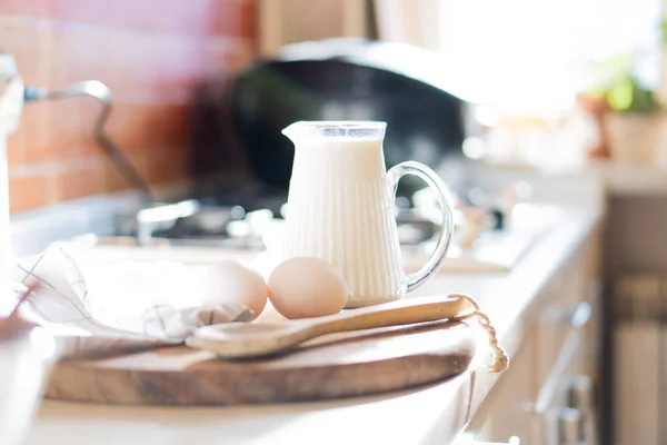 Leche fresca y huevos en tablero de madera en el interior de la cocina casera real con luz natural —  Fotos de Stock
