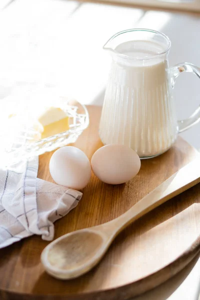 Fresh milk and eggs on wooden board in real home kitchen interior with natural light — Stock Photo, Image