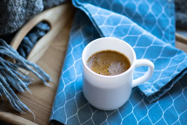 Café negro en taza blanca con elegante servilleta azul en bandeja de madera — Foto de Stock