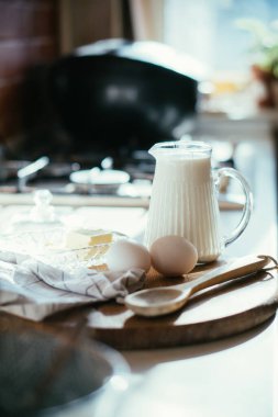 Tahtadaki taze süt ve yumurta. Gerçek ev mutfağında. İçi doğal ışıkla dolu.