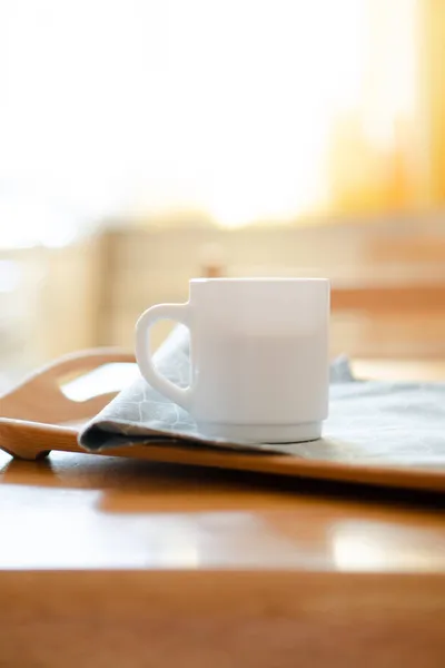 White coffee mug with napkin on table in real kitchen interior with bright natural sunlight — Stock Photo, Image