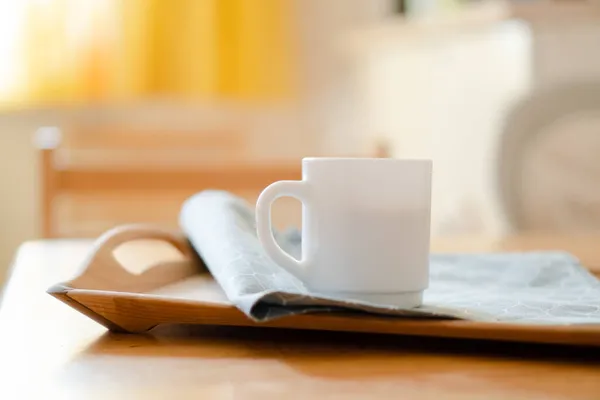 Taza de café blanco con servilleta en la mesa en el interior de la cocina real con luz solar natural brillante —  Fotos de Stock