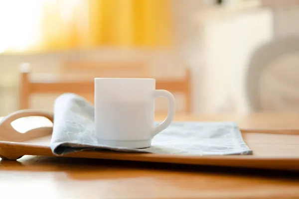 Taza de café blanco con servilleta en la mesa en el interior de la cocina real con luz solar natural brillante —  Fotos de Stock