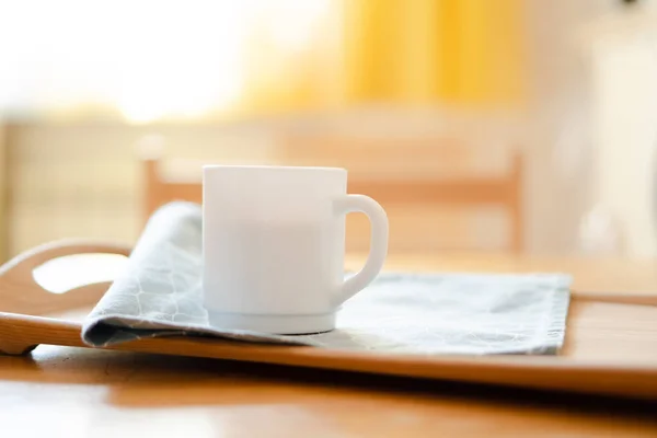 Taza de café blanco con servilleta en la mesa en el interior de la cocina real con luz solar natural brillante — Foto de Stock