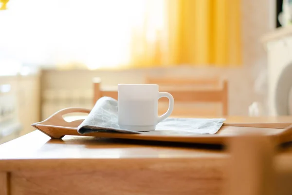 Taza de café blanco con servilleta en la mesa en el interior de la cocina real con luz solar natural brillante — Foto de Stock