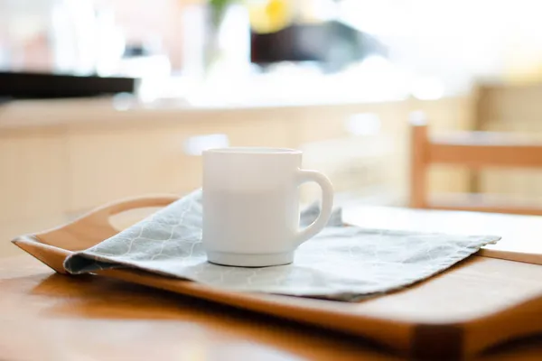 Weiße Kaffeetasse mit Serviette auf dem Tisch in echtem Kücheninterieur mit hellem Tageslicht — Stockfoto