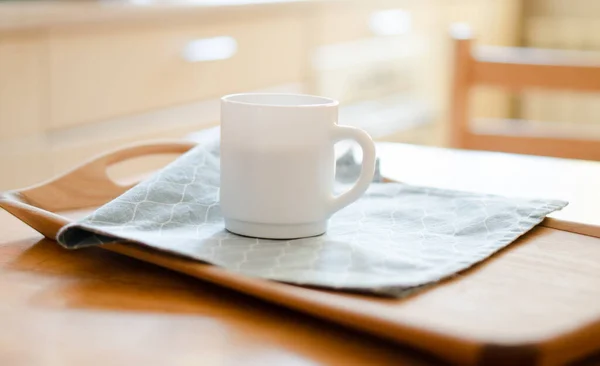 Beyaz kahve fincanı ve mutfak masasının üstünde peçete. Parlak güneş ışığı var. — Stok fotoğraf