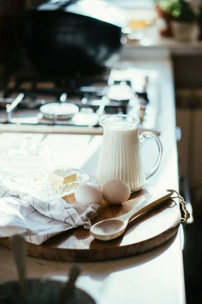 Leche fresca y huevos en tablero de madera en el interior de la cocina casera real con luz natural — Foto de Stock