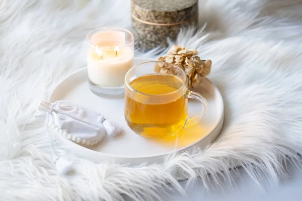 Cup of herbal tea and burning candle on round white decorative tray — Stock Photo, Image