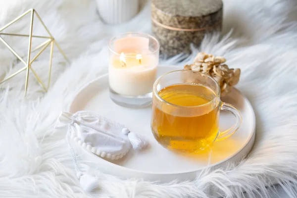 Taza de té de hierbas y vela ardiente en bandeja decorativa redonda blanca — Foto de Stock