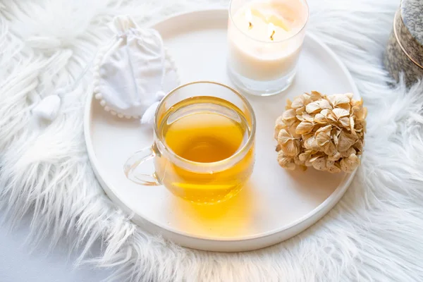 Κύπελλο φυτικό τσάι και κερί καύση σε στρογγυλό λευκό διακοσμητικό δίσκο — Φωτογραφία Αρχείου